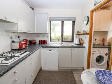 A kitchen with a gas stove dishwasher washing machine and red appliances at Pinegarth Catton near Allendale