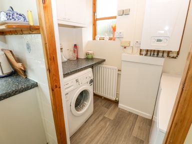 A laundry room with a washing machine countertop radiator and boiler at Pinegarth in Catton near Allendale