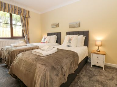 A bedroom with two single beds bedside table with lamp and window with curtains at Pinegarth Catton near Allendale