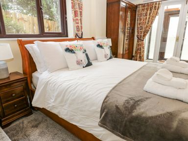 A bedroom with a wooden bed with white bedding and cow print pillows at Pinegarth in Catton near Allendale