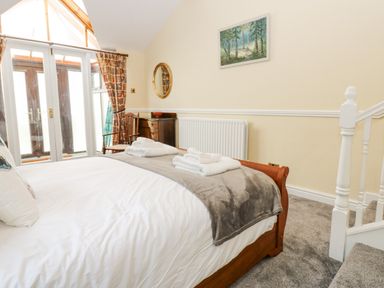 A bedroom with a bed folded towels wooden furniture and glass doors at Pinegarth Catton near Allendale