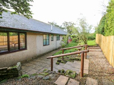 A paved walkway with handrails next to a building and a garden with a wooden fence at Pinegarth in Catton near Allendale