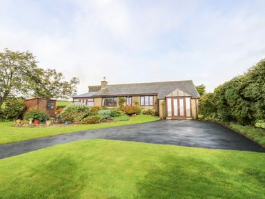 A single story house with a driveway and garden with bushes and trees at Pinegarth in Catton near Allendale