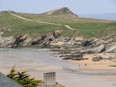 A coastal path with people walking on grass and rocky cliffs overlooking a sandy beach at 11 Ebbtide in Porth
