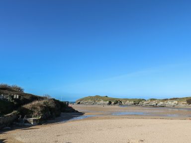 A sandy beach with rocky hills and clear blue sky at 11 Ebbtide in Porth