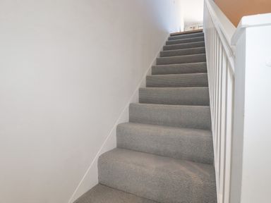 A carpeted staircase with white walls and a white banister at 11 Ebbtide in Porth