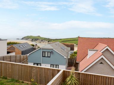 Houses with fenced yards near a beach with a grassy hill in the background at 11 Ebbtide in Porth