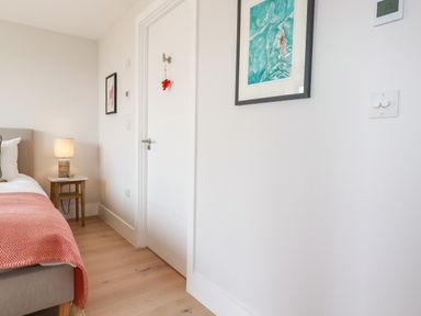 A bedroom with a bed lamp and framed pictures on the walls at 11 Ebbtide in Porth