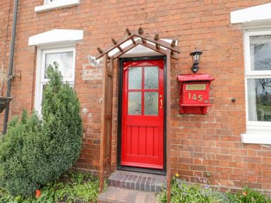 A red door with a red mailbox numbered 145 on a brick house exterior at Dobbies Den in Bewdley