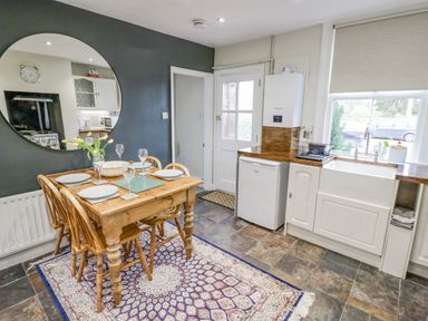A kitchen with wood dining table and chairs next to a sink and a window at Dobbies Den in Bewdley