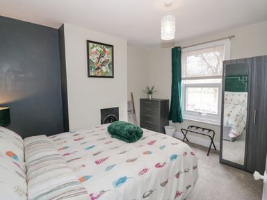 A bedroom with a bed a chest of drawers a wardrobe with mirror and a window at Dobbies Den in Bewdley