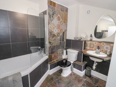A bathroom with a bathtub shower toilet and sink at Dobbies Den in Bewdley