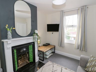 A living room with a fireplace a wall mirror TV on a wall and a window at Dobbies Den in Bewdley