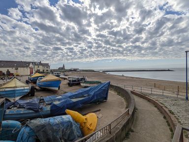 A beach with boats on the shore and buildings in the background at Fairwinds in Newbiggin-By-The-Sea