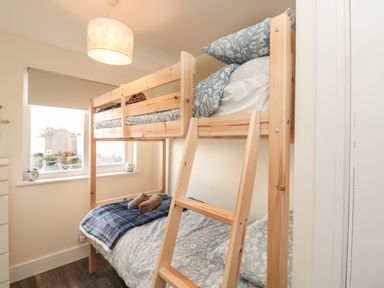 A bedroom with a wooden bunk bed next to a window with blinds at Fairwinds in Newbiggin-By-The-Sea