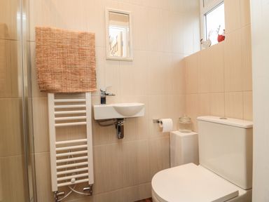 A small bathroom with a toilet sink towel radiator and a window at Fairwinds in Newbiggin-By-The-Sea