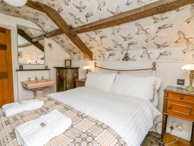 A bedroom with double bed folded towels bedside tables and wooden beams at Ty Sinsir in Tretower