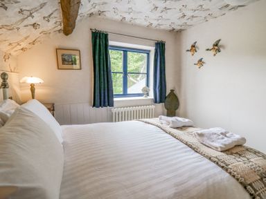 A bedroom with a bed and a window with blue curtains at Ty Sinsir in Tretower