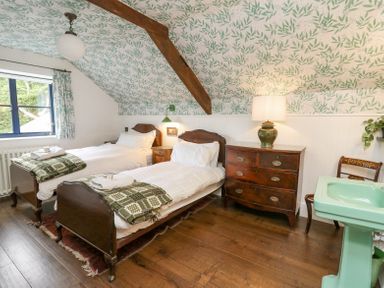 A bedroom with two single beds a wooden chest of drawers and a green sink at Ty Sinsir in Tretower
