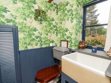 A bathroom with a vintage toilet wooden seat and a large basin under a window at Ty Sinsir in Tretower