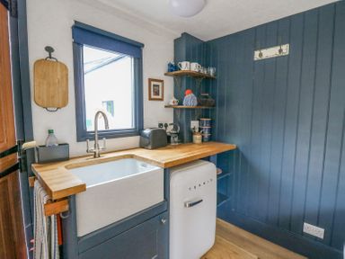 A kitchen corner with a white sink wooden countertop toaster and a small white fridge at Ty Sinsir in Tretower