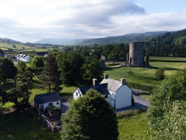 A countryside scene with white houses trees a stone tower and rolling hills at Ty Sinsir in Tretower