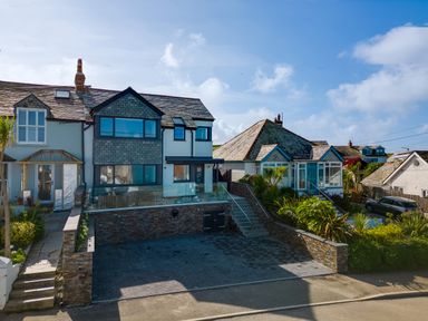 A residential street with two houses one with a modern extension and a paved driveway at 12 Tintagel Terrace in Port Isaac