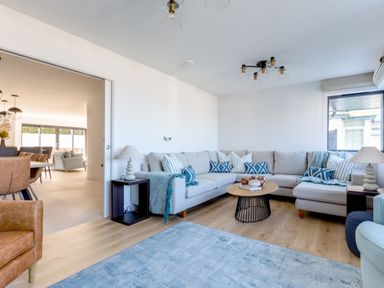 A living room with a beige sectional sofa and blue patterned cushions at 12 Tintagel Terrace in Port Isaac