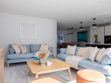 A living room with two blue sofas a wooden coffee table and brown stools at 12 Tintagel Terrace in Port Isaac