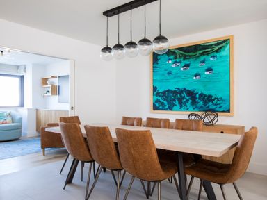 A dining room with a wooden table and eight brown chairs with a blue painting on the wall at 12 Tintagel Terrace in Port Isaac