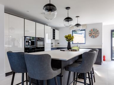 A modern kitchen with a large island and four stools at 12 Tintagel Terrace in Port Isaac