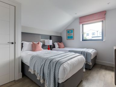 A bedroom with two single beds with grey headboards and blue throws at 12 Tintagel Terrace in Port Isaac