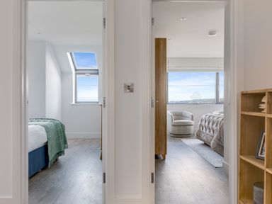 View through two doorways into two bedrooms with windows and furniture at 12 Tintagel Terrace in Port Isaac