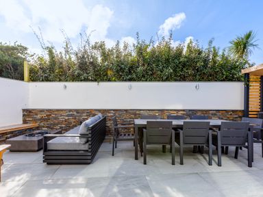 An outdoor patio area with a gray sectional sofa and a dining table with chairs at 12 Tintagel Terrace in Port Isaac