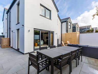 An outdoor patio area with a black dining table and chairs next to a white building at 12 Tintagel Terrace in Port Isaac
