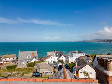 Houses near the coastline with the sea and cliffs in the background at 12 Tintagel Terrace in Port Isaac