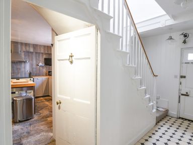 A hallway with stairs and a door leading to a kitchen with wooden cabinets at Braeside Lyme Regis