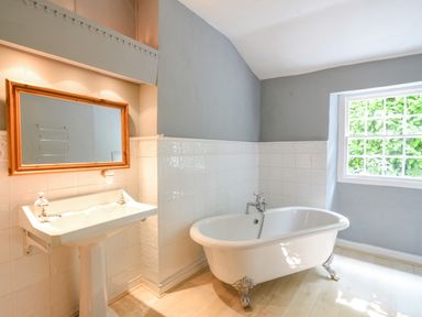 A bathroom with a free standing bathtub a sink with a mirror and a window at Braeside Lyme Regis
