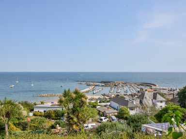 A harbor with boats docked and houses with gardens near the coastline at Braeside Lyme Regis