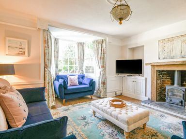 A living room with blue sofas and a tufted ottoman in front of a fireplace at Braeside in Lyme Regis