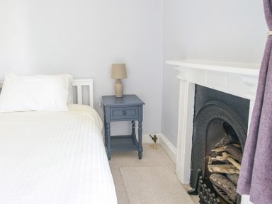 A bedroom with a bed a bedside table with a lamp and a fireplace at Braeside in Lyme Regis