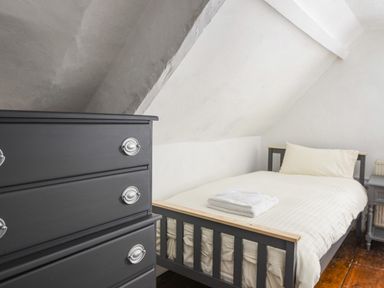 A bedroom with a bed and folded towels on it and a chest of drawers at Braeside in Lyme Regis