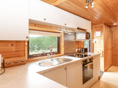 A kitchen with a sink stove microwave and cabinets at Ennerdale Lodge Burnside Park near Keswick