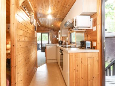 A kitchen with wooden walls and ceiling and white cabinets at Ennerdale Lodge Burnside Park near Keswick