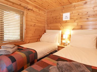 A bedroom with two single beds and wooden walls at Ennerdale Lodge Burnside Park near Keswick