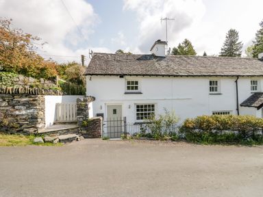 A white stone cottage with slate roof and small garden at Old Farm Cottage in Skelwith Fold