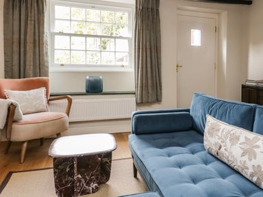 A living room with a blue sofa a peach armchair and a marble coffee table at Old Farm Cottage in Skelwith Fold