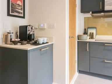 A kitchen corner with coffee machine cups and containers on countertops at Old Farm Cottage in Skelwith Fold