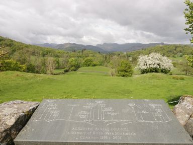 A stone plaque with names of hills with a green field and trees and mountains in the background at Old Farm Cottage in Skelwith Fold