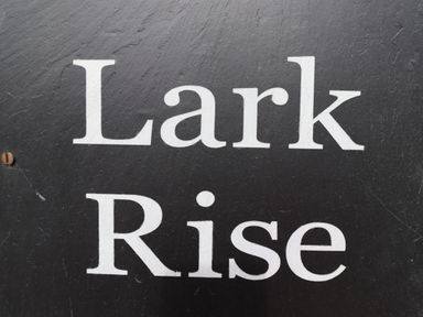 A black sign with white text that reads Lark Rise